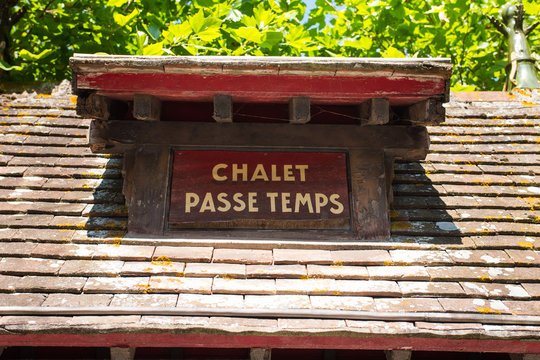 "Chalet passe-temps" sign, Cabourg, Nomandy. France. July 2019. Beautiful name on a typical french roof. Summer day with luxurious nature in the background.