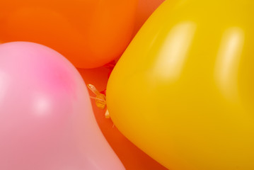 Orange, yellow, pink ballons on orange background.
