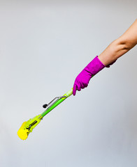 Cleaning the house topic: human hand in yellow rubber gloves holding a yellow mop isolated on a white background in studio