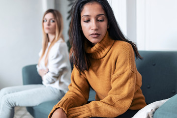 Two upset friends not talking to each other after fight on the sofa at home.