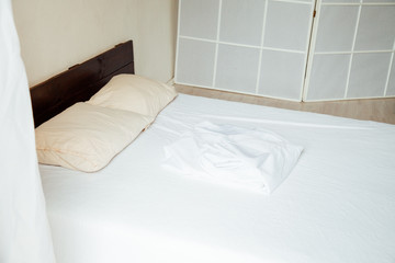 empty bed in the interior of the white bedroom after sleeping in the morning