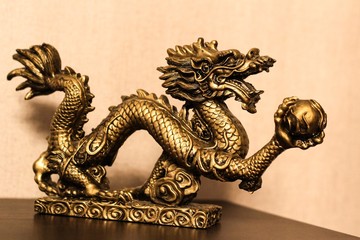 Golden dragon with a ball. A souvenir in the form of a dragon.