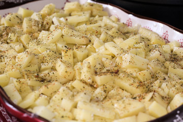 Raw potatoes with spices cubes before baking