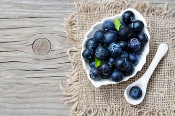 Freshly picked organic blueberries in a white bowl on a burlap cloth background.Blueberry. Bilberries.Healthy eating,vegan food or diet concept with copy space.Selective focus.