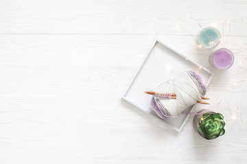 Cotton yarn, the beginning of knitting, knitting needles and succulent in a pot. White background.