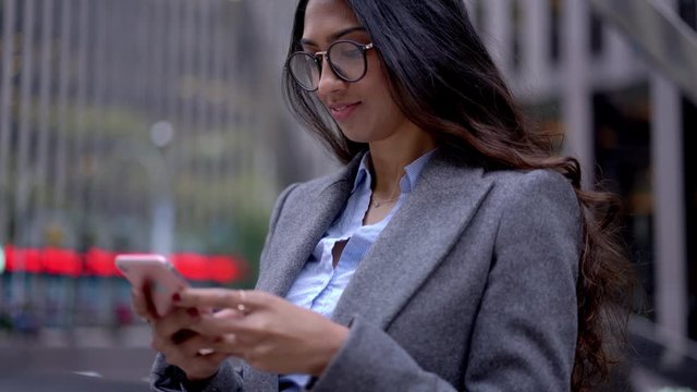 South Asian woman in formal clothing checking mobile browser with financial website connected to 4g wireless for surfing internet, Indian economist chatting with customers during online consultancy