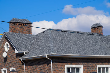 Asphalt shingle. Decorative bitumen shingles on the roof of a brick house.