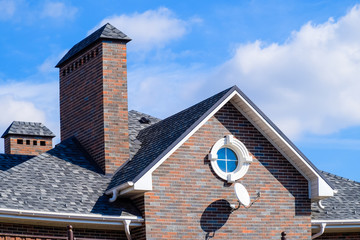 Asphalt shingle. Decorative bitumen shingles on the roof of a brick house.