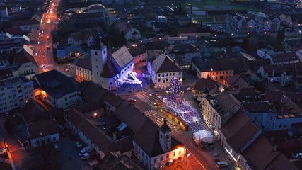 Christmas fair with decoration and bright lights on main square of small town in Europe, aerial view of old medieval town center