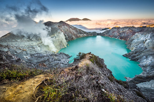 Wide angle panorama photo of colorful sunrise at volcano crater Kawah Ijen with sulphur acid lake in Java, Indonesia. Famous, attractive and popular place for photographers and tourists close to Bali.