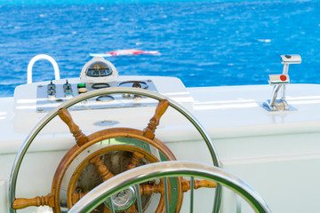 Obraz premium Yacht steering wheel on blue sky background. The yacht's steering wheel sails on the sea