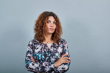 Disappointed brunette caucasian young woman keeping hands crossed, looking unhappy over isolated...