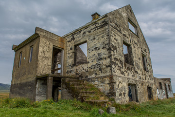 Fototapeta premium View of an old abandoned destroyed house. Ladder overgrown with green grass