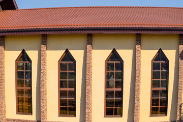 building with yellow walls and a red-brown roof. Modern materials of finish and roofing.