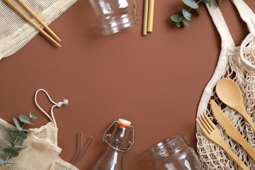 Zero waste concept. Flat lay Eco friendly wooden cutlery, string bag, glass jar and bottle on brown...