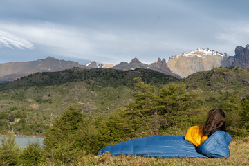 Girl in sleeping bag in mountains near lake