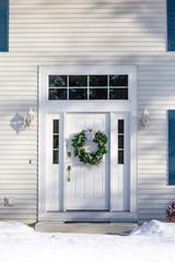 Front of a house  with a Christmas wreath on the front door in winter vertical