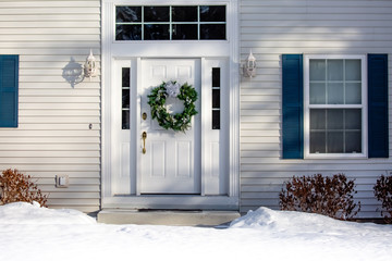 Front of a house  with a Christmas wreath on the front door in winter