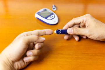 Man using lancelet on finger checking blood sugar level.