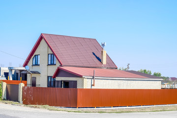 House with plastic windows and roof of corrugated sheet. Roofing of metal profile wavy shape on the house with plastic windows