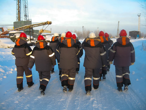 a group of workers in work clothes and helmets, rear view