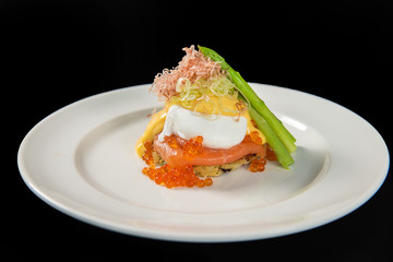 Delicious breakfast with Eggs Benedict and salmon caviar (Ikura) on the black background