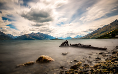 Long exposure photo of boulders in lake with dramatic sky.