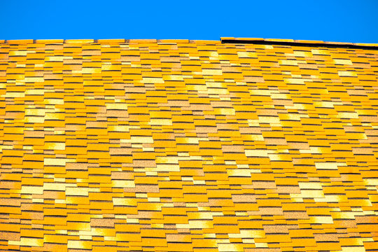 Roof from multi-colored bituminous shingles. Patterned bitumen shingles.