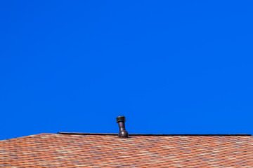 Roof from multi-colored bituminous shingles. Patterned bitumen shingles. Ventilation on the roof.