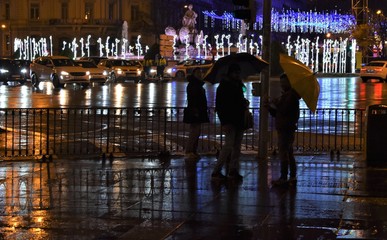 Rainy night in the city with the blurred reflection of the neon lights on the wet pavement
