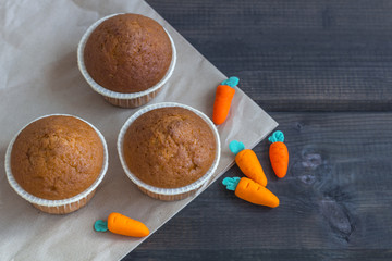 Freshly baked carrot muffins decorated marzipan carrots on wooden background. National Carrot Cake Day.