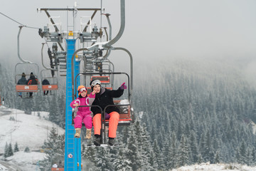 Happy family enjoying winter vacations in mountains . Mother with her daughter on the ski lift.