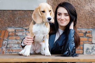 Pretty brunette girl takes in the arms of his beloved cute dog. Girl spends time outdoors with dog,...