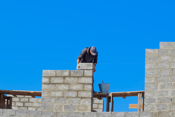 The builder builds the wall of the house from the cinder block. Worker at the construction site.