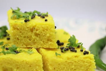 Gujarati Khaman Dhokla or Steamed Gram Flour cakes with spices tempering and garnished with...
