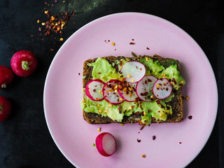 Dark rye bread avocado toast with radishes, red onion and chili flakes.