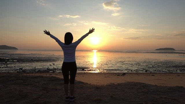 Female with happy and healthy life at the dawn,hd slow motion.  Woman outstretching arms facing to a beautiful golden sun  challenging to a new day at sea sunrise,hope concept.  