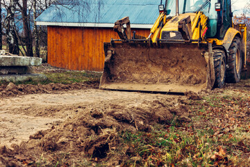 The excavator works on the street of the countryside, in the construction of roads.