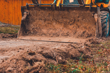 The excavator works on the street of the countryside, in the construction of roads.