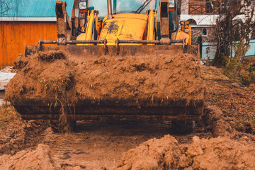The excavator works on the street of the countryside, in the construction of roads.