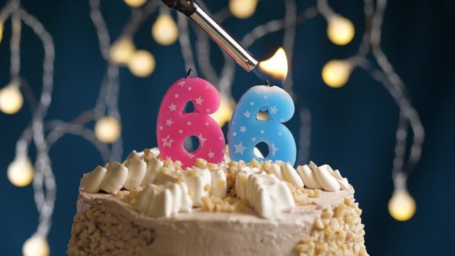 Birthday cake with 66 number pink candle on blue backgraund. Candles are set on fire. Slow motion and close-up view