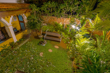 Lit up courtyard at night with wooden bench
