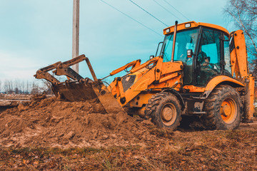Obraz premium Excavator with a large iron bucket on a construction site during road works, Backhoe dig the ground for the foundation.
