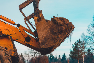 Closeup of a large bucket excavator digging the ground to set the road.