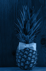 Blue pineapple with bow tie, flatlay background. Healthy ftropical fruit, vegan food banner, color trends wallpaper. Minimal creative social media picture top view. Minimalism style, trendy toning.