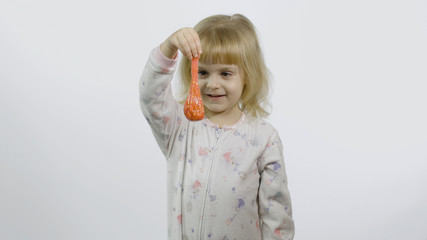 Kid playing with hand made toy slime. Child having fun making orange slime