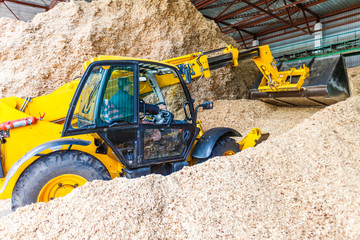 Sawmill. Loading sawdust. Yellow wheel front end loader working