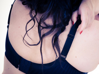 Woman back view putting on her bra lingerie.