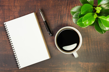 Top view of open school notebook with blank pages, Pen, Plant and Coffee cup on wooden table...