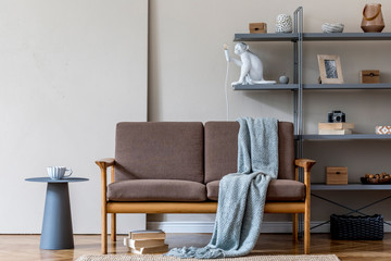 Stylish interior of living room at cozy apartment with brown wooden sofa, coffe table, gray bookstand, plaid and elegant accessories. Beige and japandi concept. Modern home staging. Template.